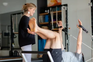 Un insegnante guida una persona in un esercizio di Pilates personalizzato, evidenziando l’importanza dell’adattamento del movimento nelle asimmetrie.